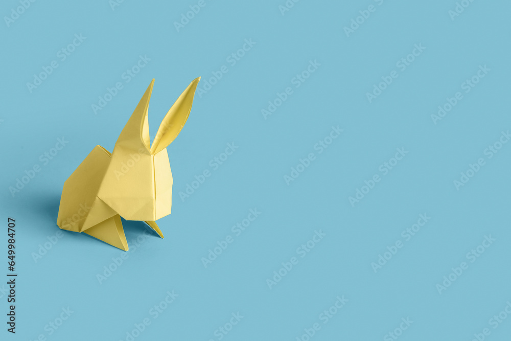 Beige origami rabbit on blue background