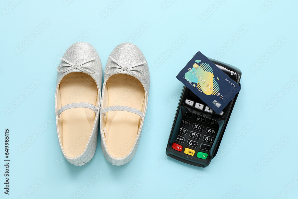 Pair of stylish childs shoes, payment terminal and credit card on color background