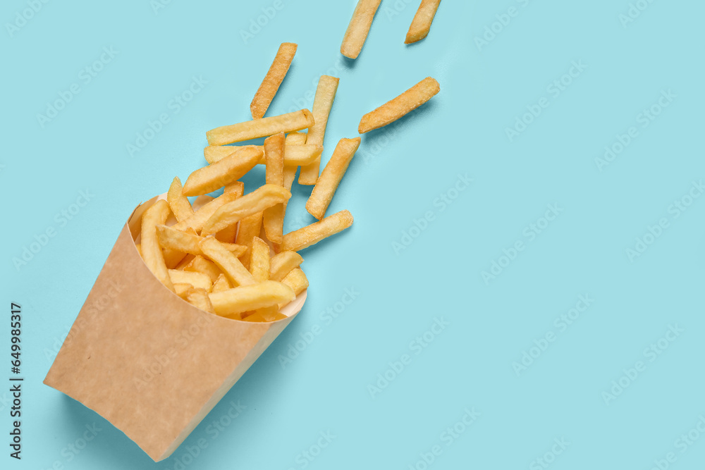 Paper bag with golden french fries on blue background