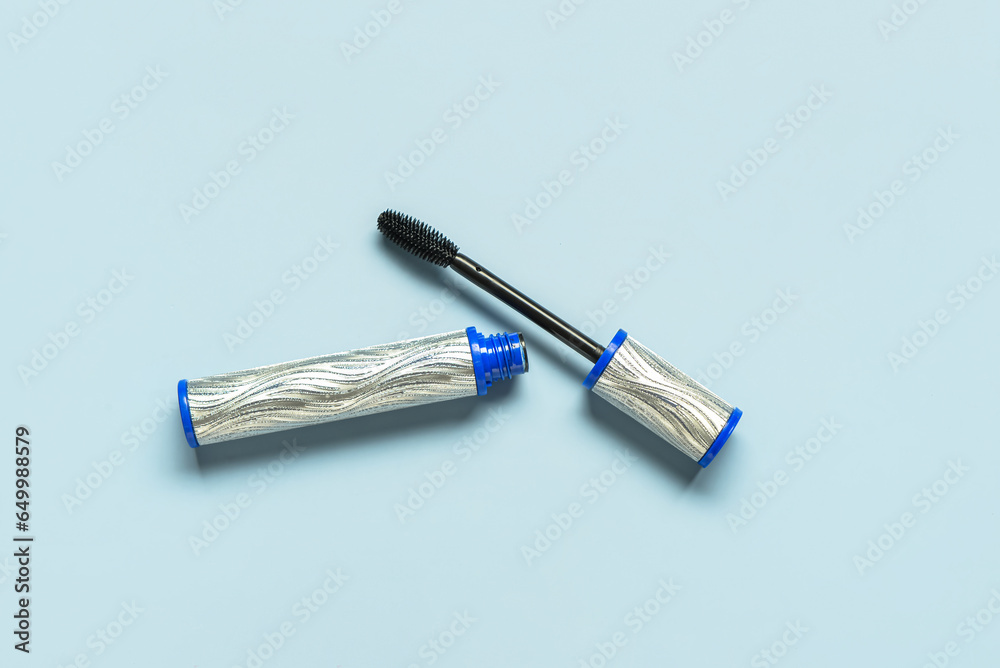 Black mascara in silver tube on blue background