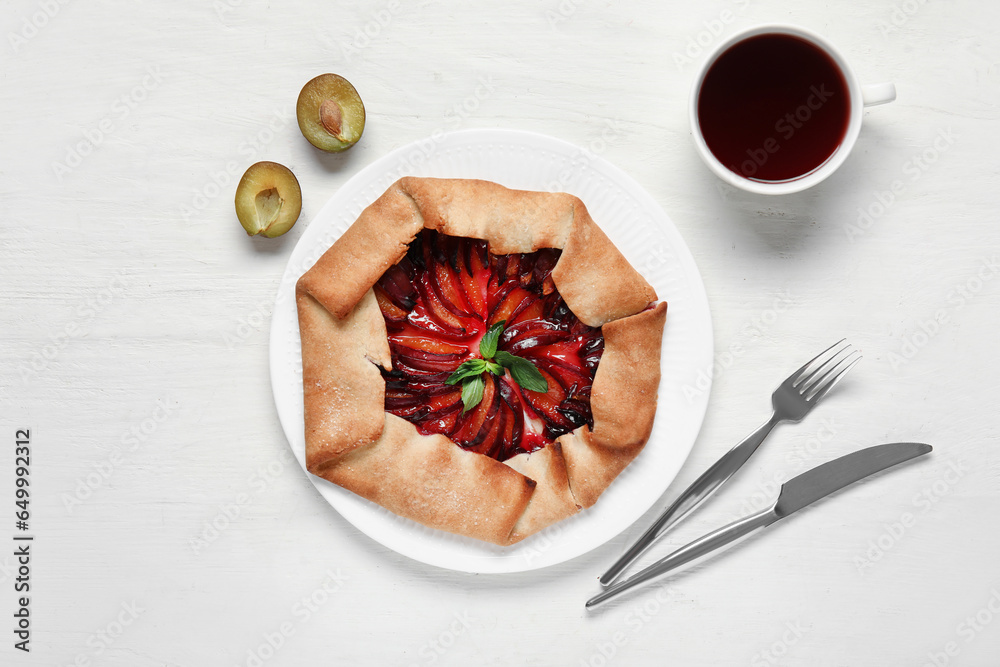 Plate of delicious plum galette with mint on white background