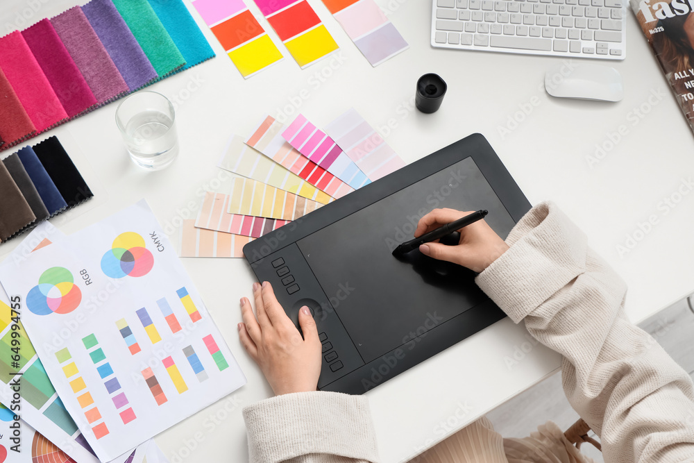 Female interior designer working with graphic tablet at table in office, top view