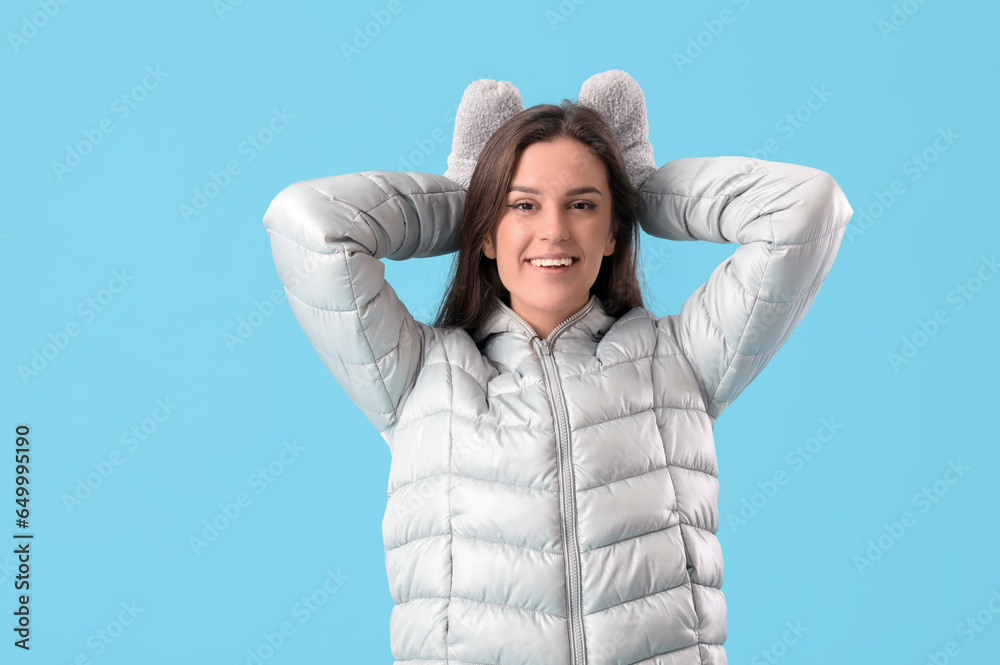 Young woman in winter clothes on blue background