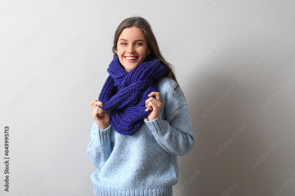 Happy young woman in winter clothes on light background