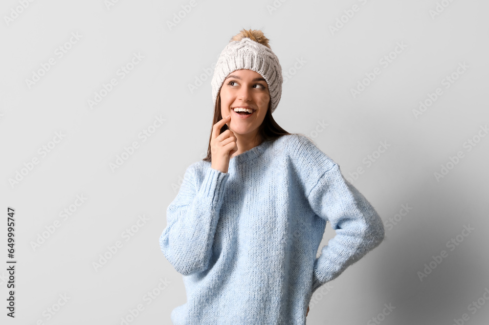 Young woman in winter clothes on light background