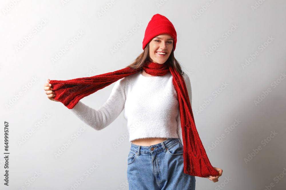 Young woman in winter clothes on light background