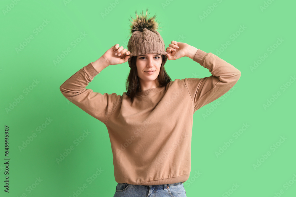 Young woman in winter clothes on green background