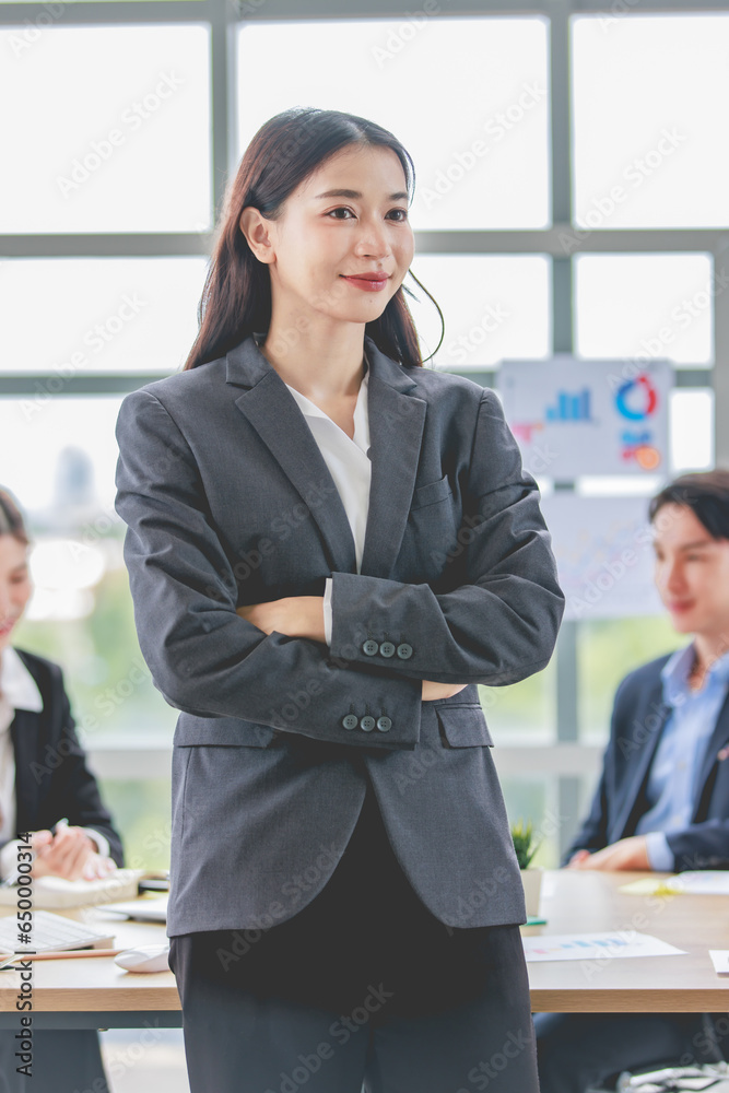 Portrait shot of Asian professional successful female businesswoman manager entrepreneur in formal suit standing smiling looking at camera in company meeting room