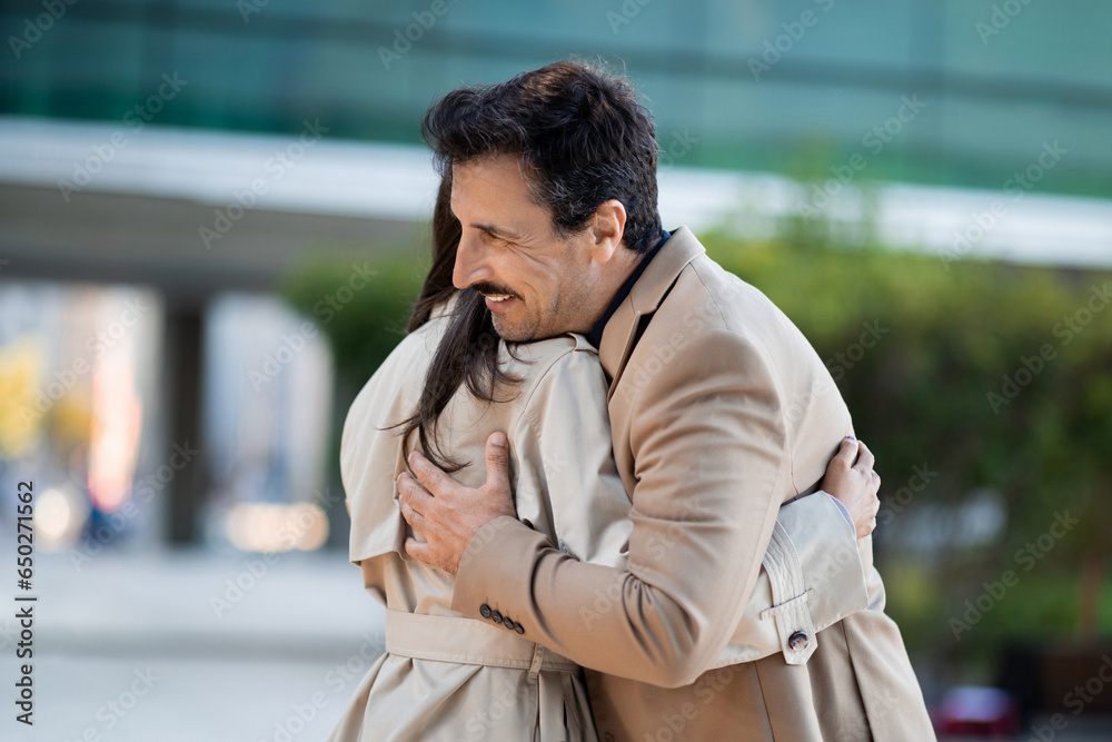 Mature people man and woman friends colleagues hugging on street