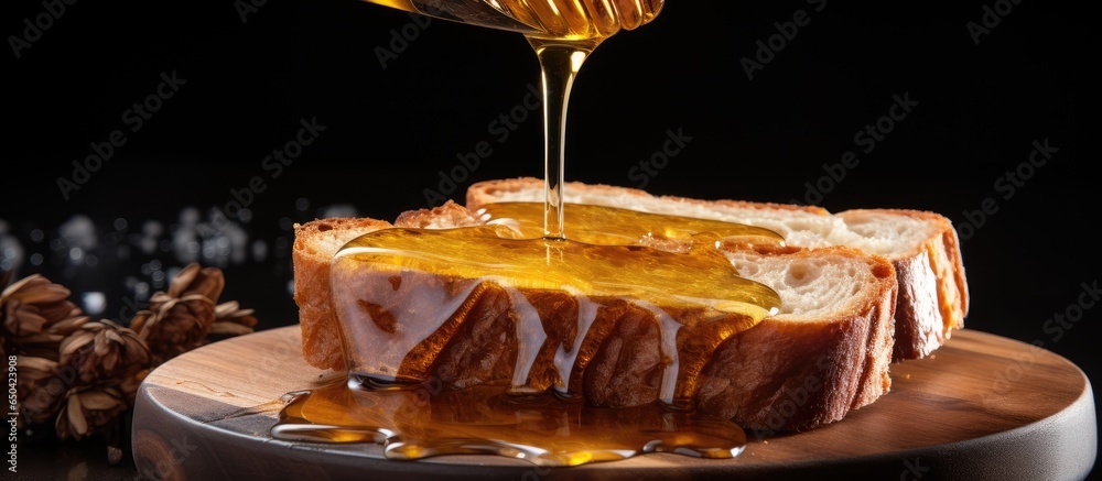 Oil being poured on toasted bread slice on wooden board closeup