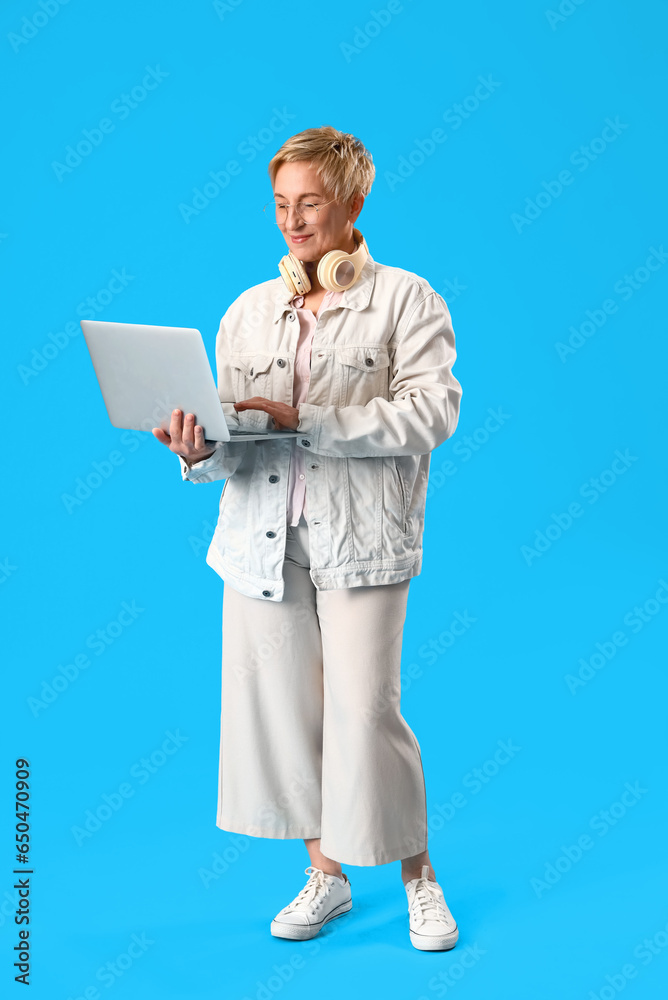 Mature female programmer working with laptop on blue background