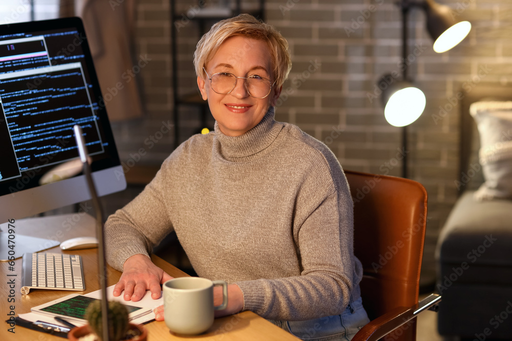 Mature female programmer working in office at night