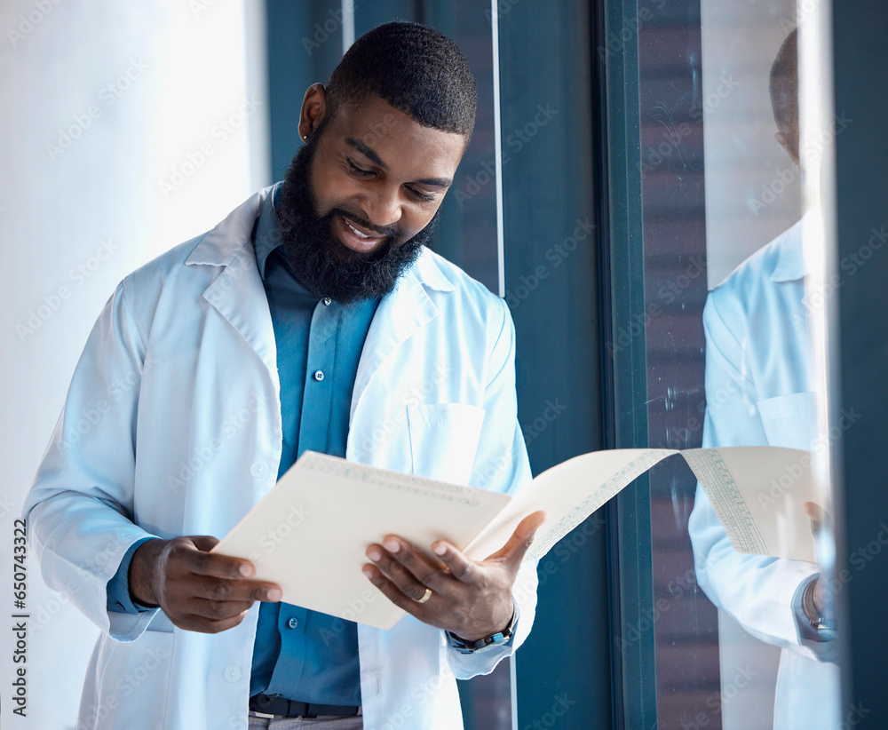 Doctor, man and reading documents, information or paperwork of patient by window in building with smile. Healthcare, professional or black person check notes, charts on paper with medical experience