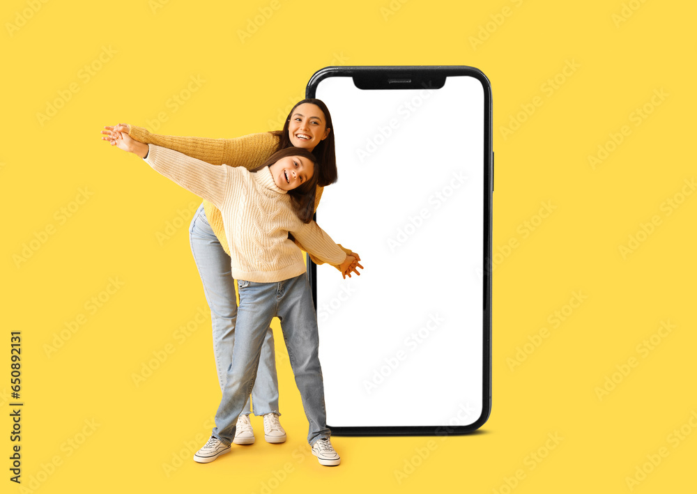 Little girl and her mother in knitted sweaters on yellow background