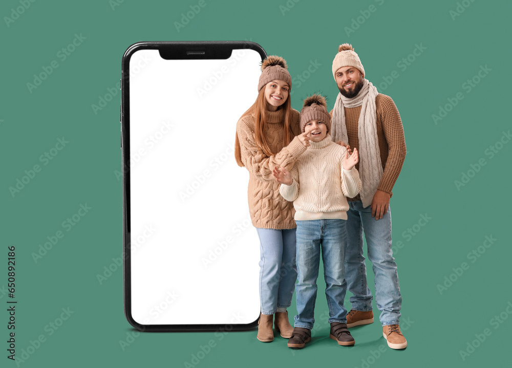 Happy parents with their little son in warm clothes on green background