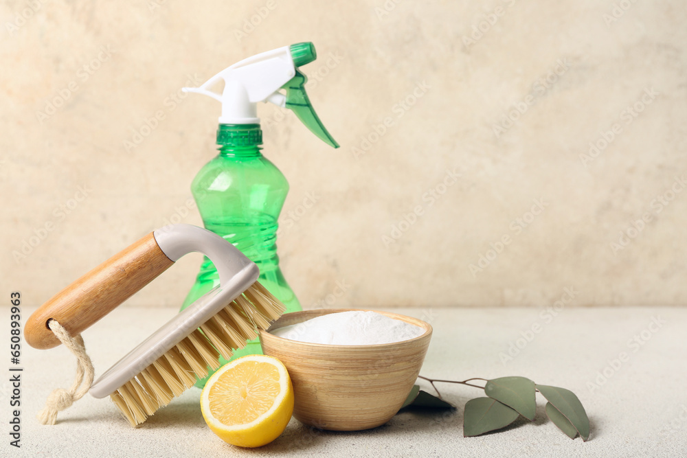 Bowl of baking soda, sprayer, cleaning brush and lemon on light table