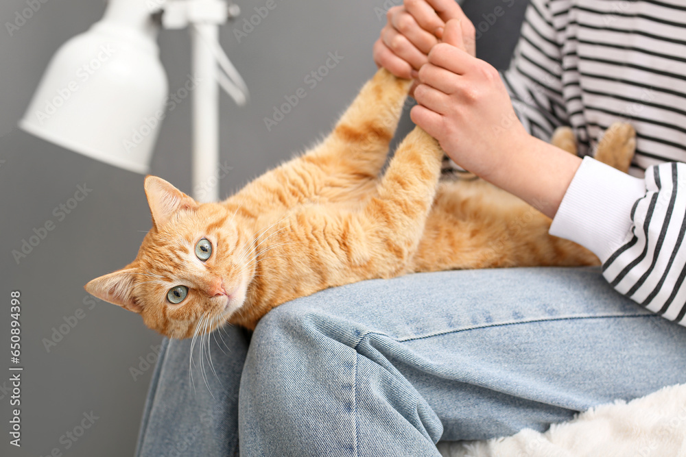 Woman with cute ginger cat sitting at home, closeup