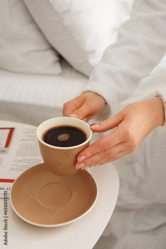 Woman in bathrobe taking cup of delicious coffee from table, closeup