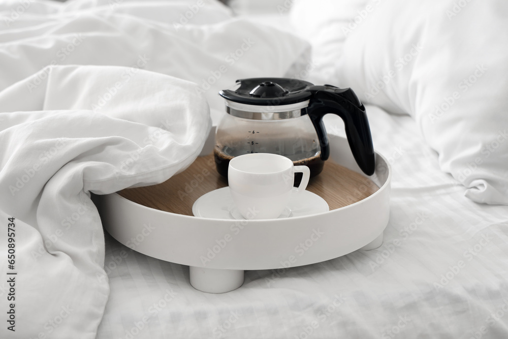 Tray with coffee pot and cup in bed