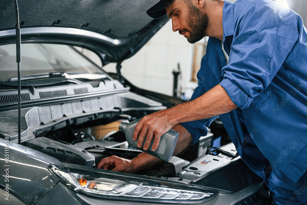 Oil can in hands. Auto mechanic working in garage. Repair service