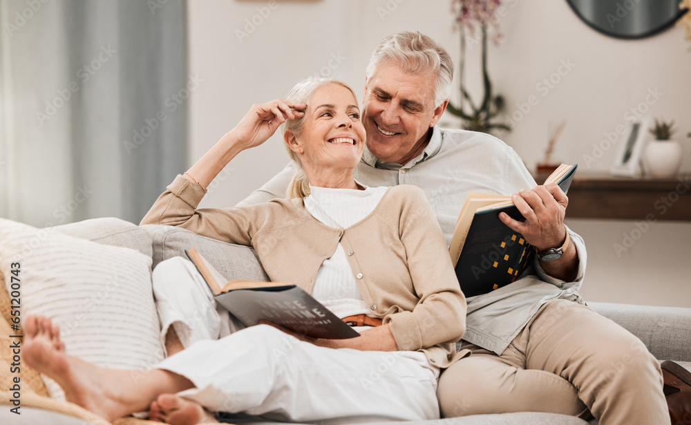 Senior, couple and reading book on a living room sofa with love, smile and retirement in a home. Elderly people, story and lounge on a couch with study for knowledge in a house happy and relax