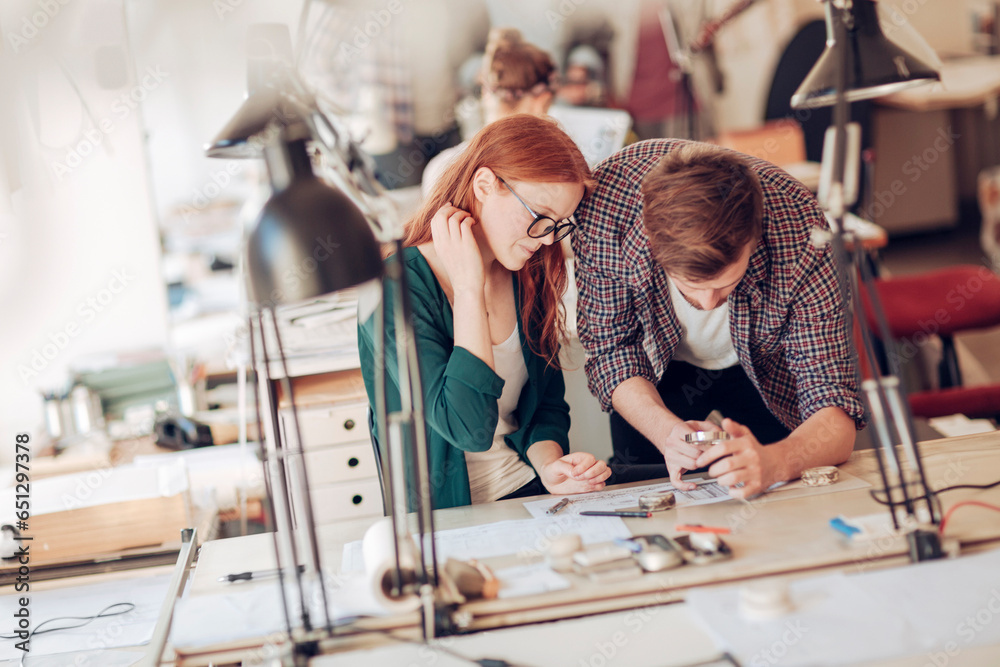 Two young and diverse architects working on a architectural drawing in a modern business office