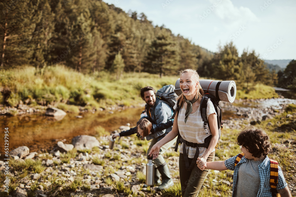 Young family crossing a creek while hiking in the forest and mountains