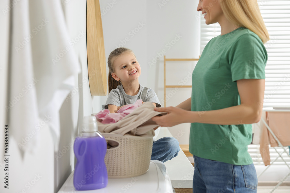 Mother and daughter taking out dirty clothes from basket in bathroom