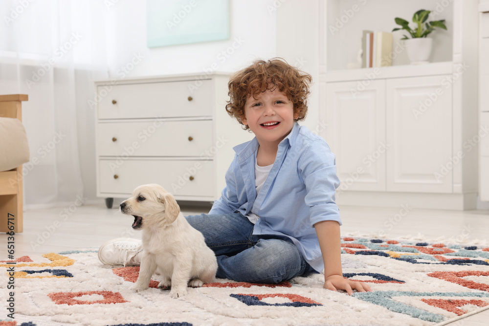 Little boy with cute puppy on carpet at home