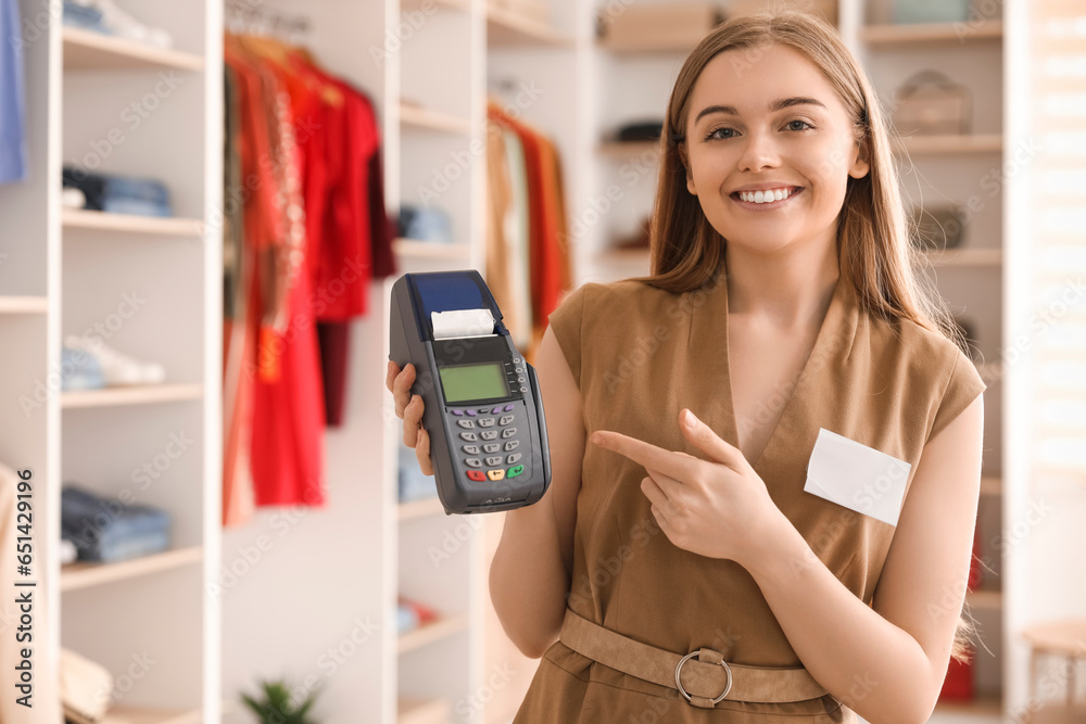 Female seller pointing at payment terminal in boutique