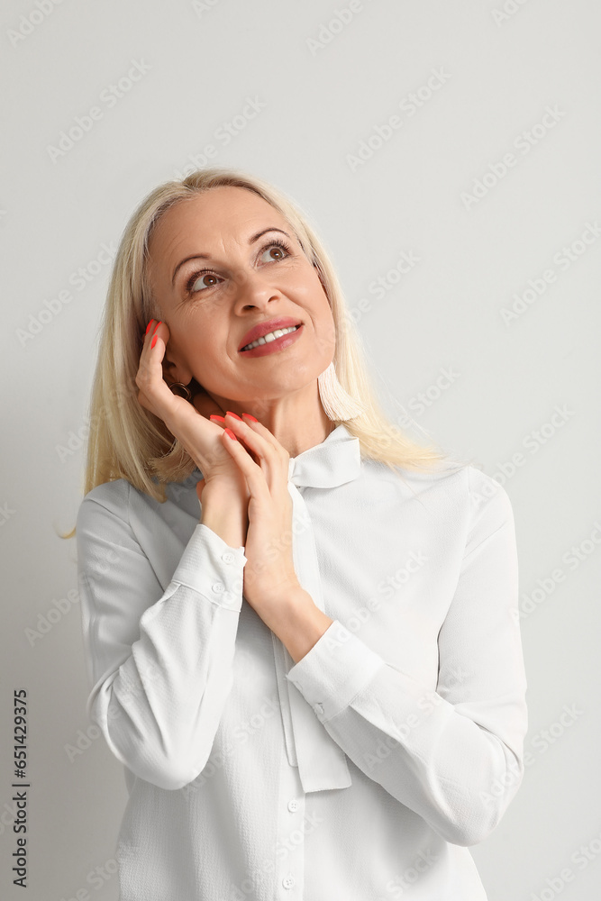 Mature blonde woman on light background