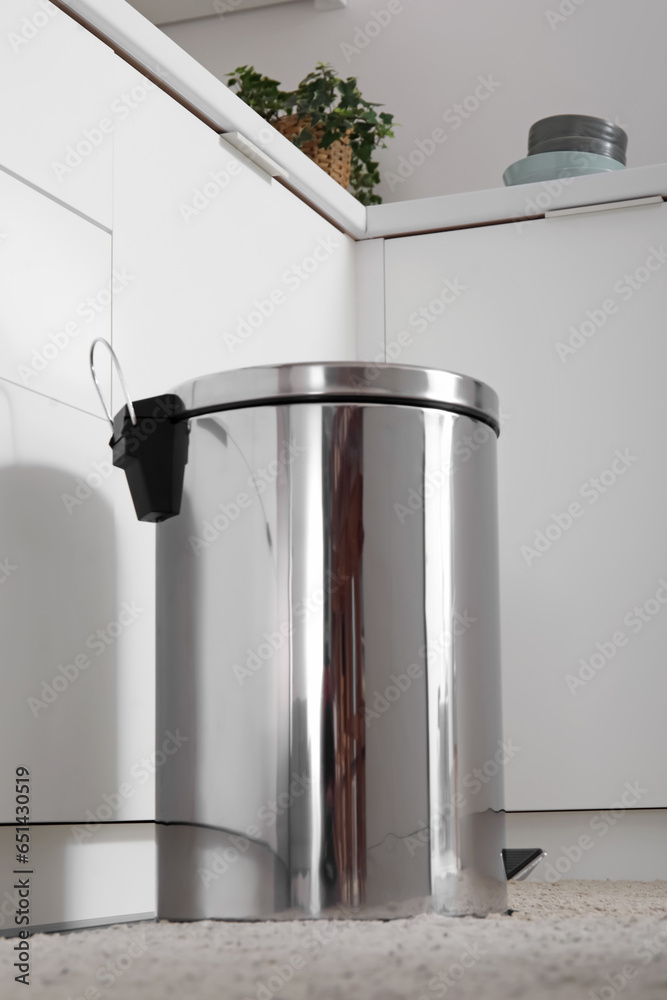 Metallic trash bin in interior of light kitchen