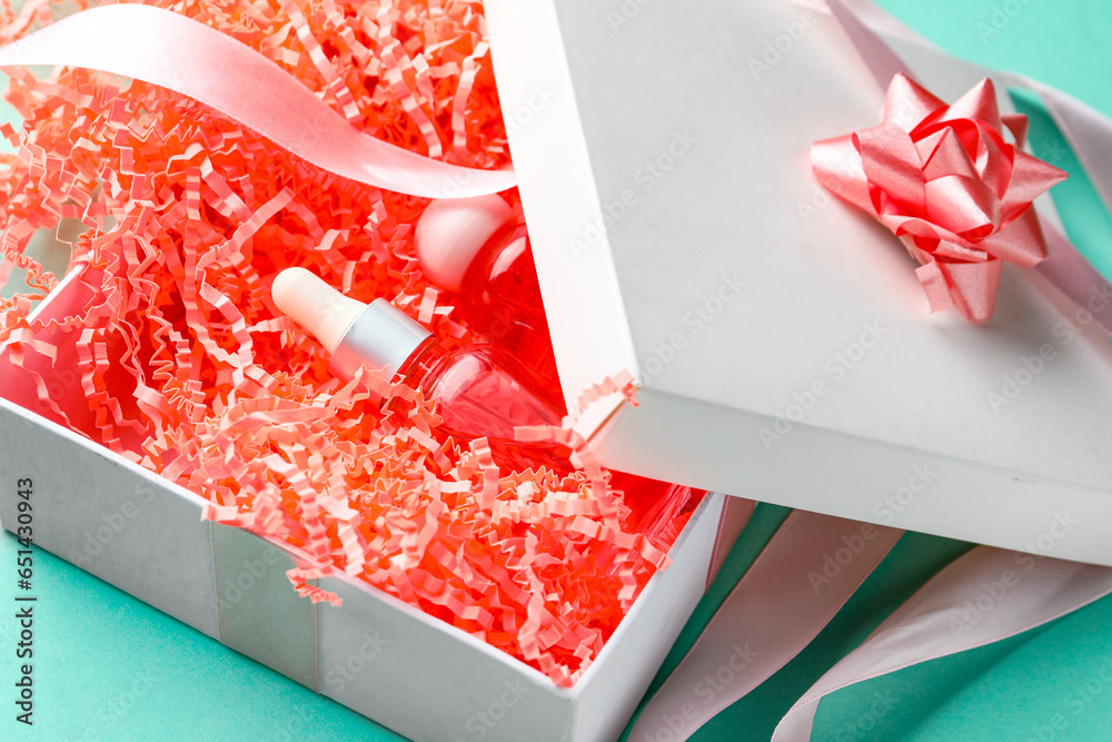 Opened gift box with cosmetics and packing paper on turquoise background