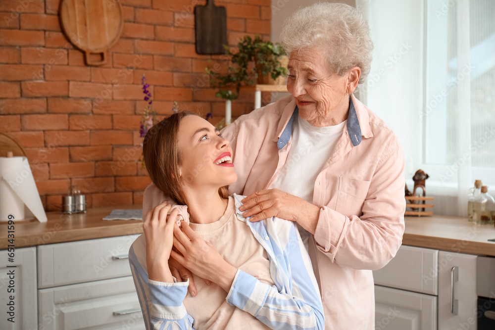 Senior woman hugging her grandmother in kitchen