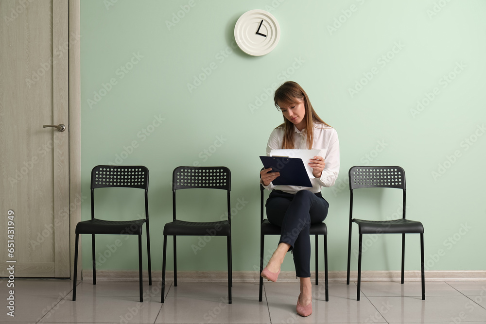 Female applicant with clipboard waiting for job interview in room