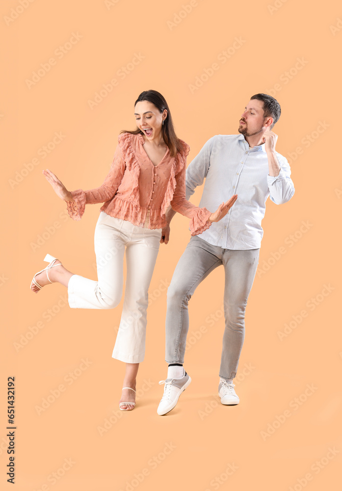 Happy young couple dancing on beige background