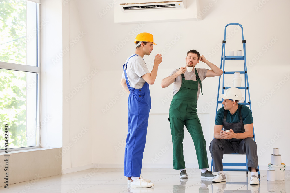 Team of male builders during coffee break in room