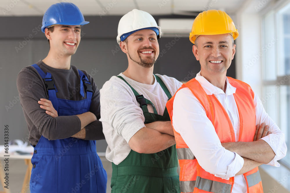 Team of male builders working in room