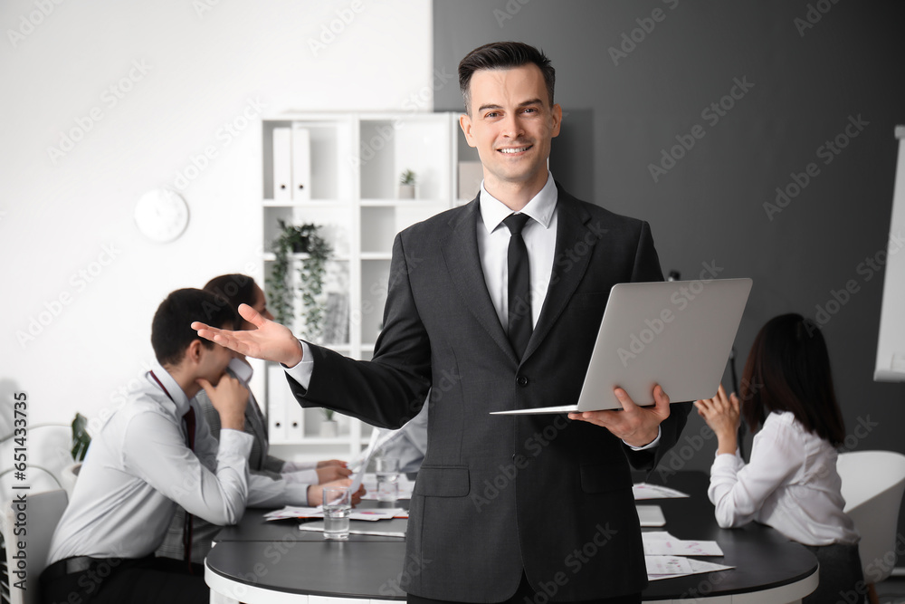 Male business consultant working with laptop in office