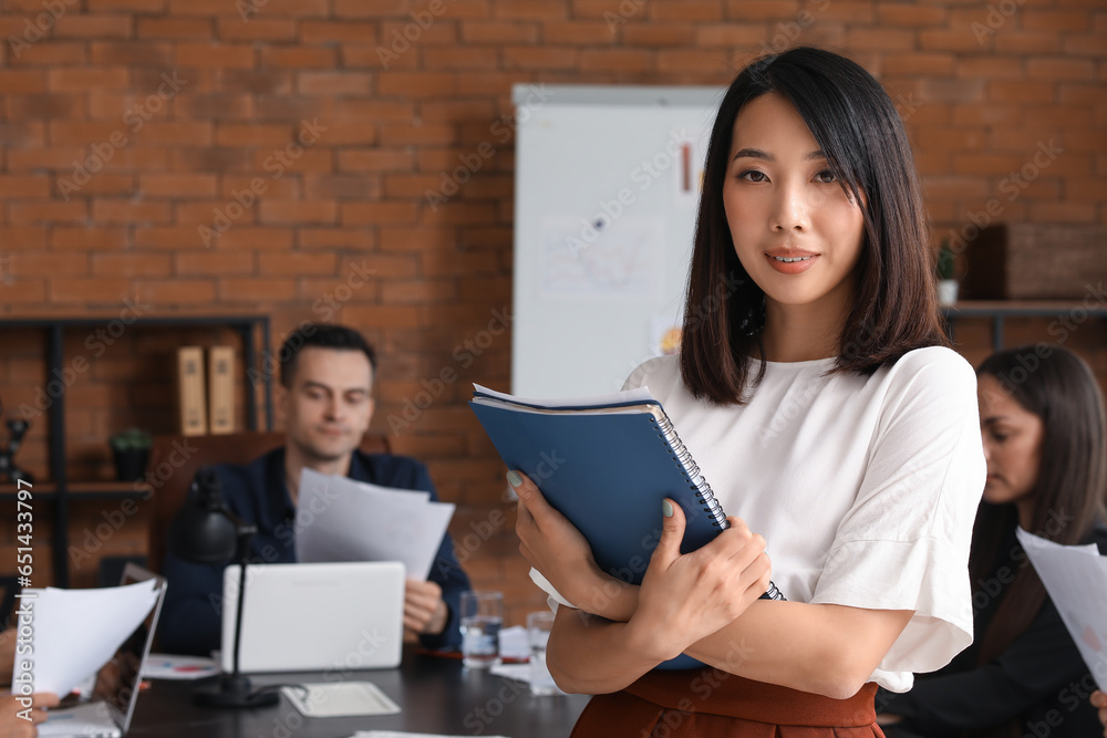 Female Asian business consultant with folder working in office