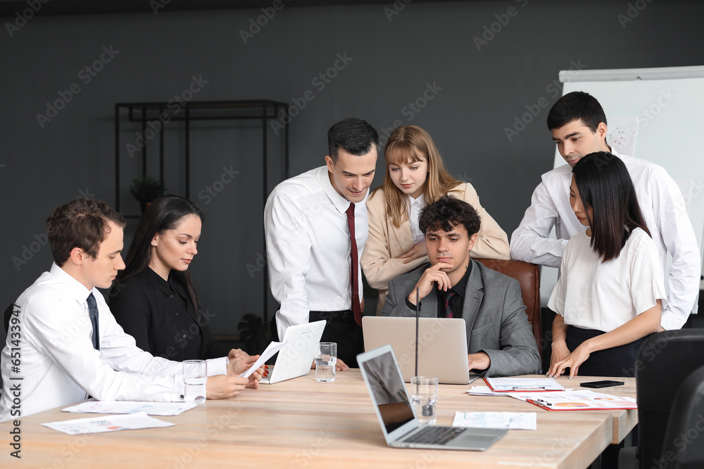 Group of business consultants working with laptop at table in office