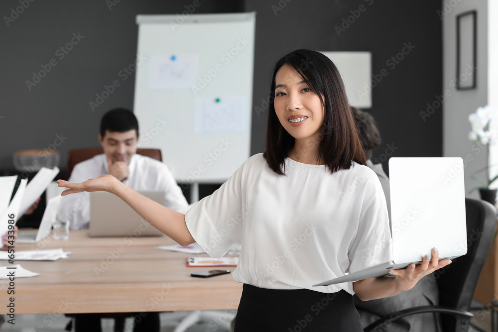 Female Asian business consultant with laptop working in office