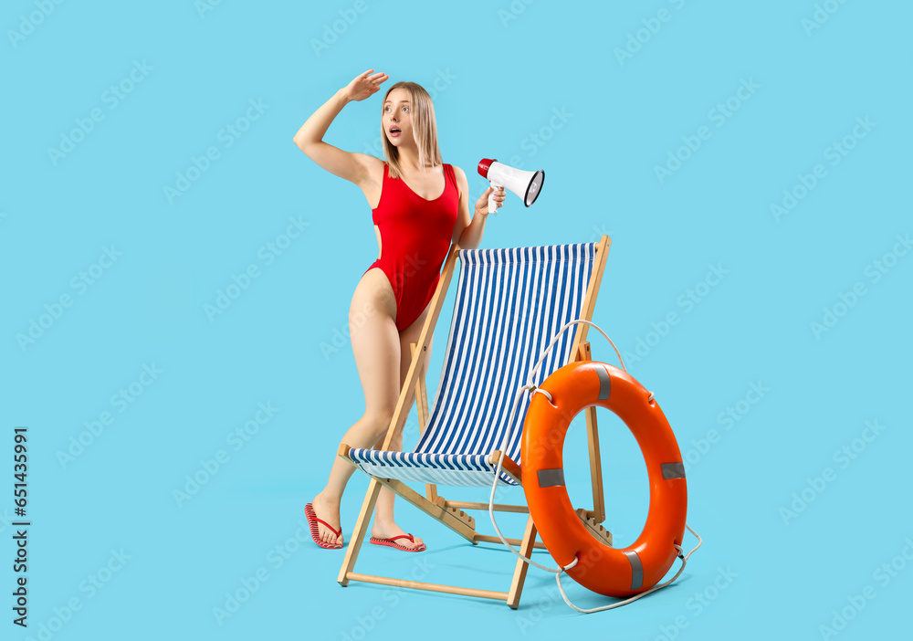 Beautiful woman with megaphone, deck chair and ring buoy on blue background