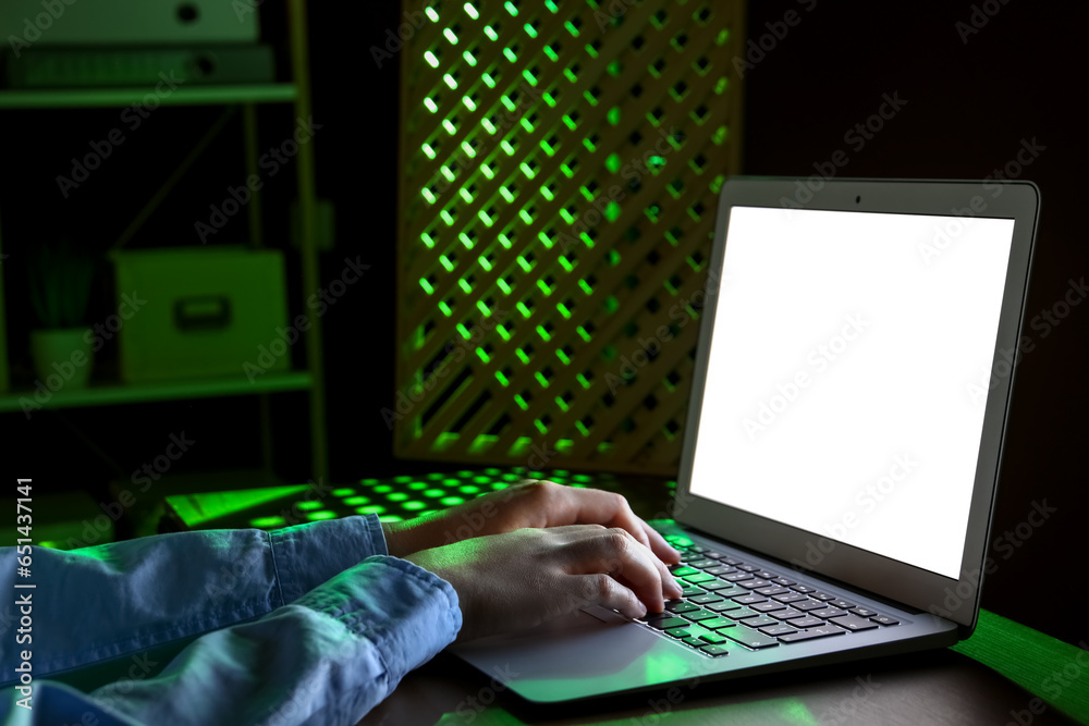 Female programmer typing on laptop keyboard at night in office, closeup