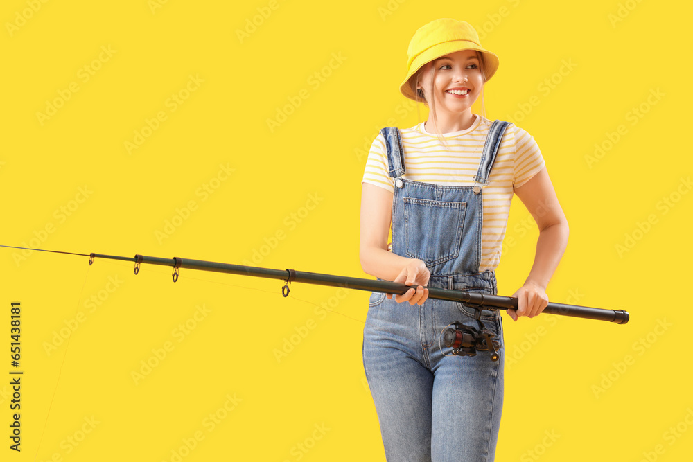 Happy young woman with fishing rod on yellow background