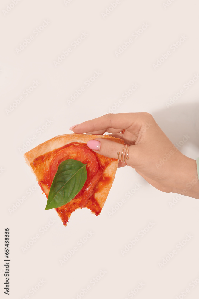 Woman holding slice of bitten pizza on white background