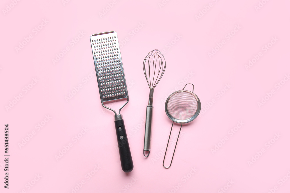 Set of stainless steel kitchen utensils on pink background