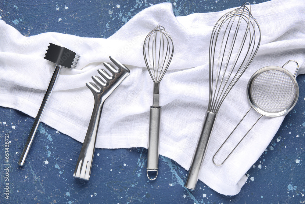 Set of stainless steel kitchen utensils and napkin on color background