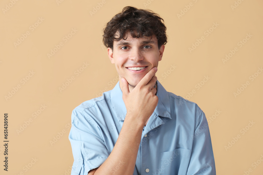 Portrait of pondering young man on beige background