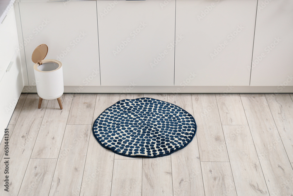 Stylish rug and trash bin on floor in kitchen